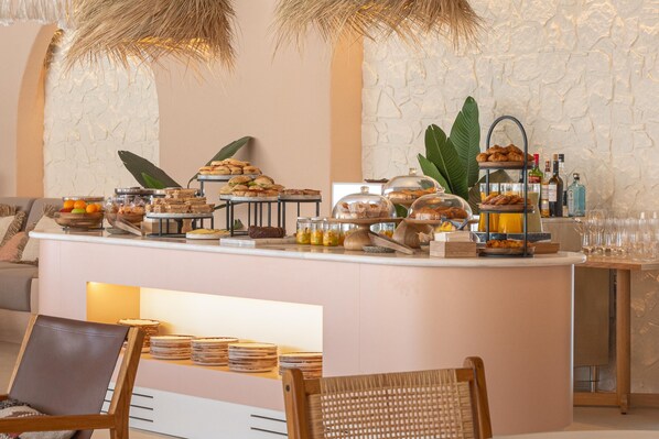 Un bufé de desayuno con diversos alimentos, una zona de bar con botellas y diferentes disposiciones de asientos.