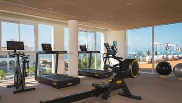 Un gimnasio moderno con máquinas de cardio, una máquina de remo y pelotas de ejercicio.