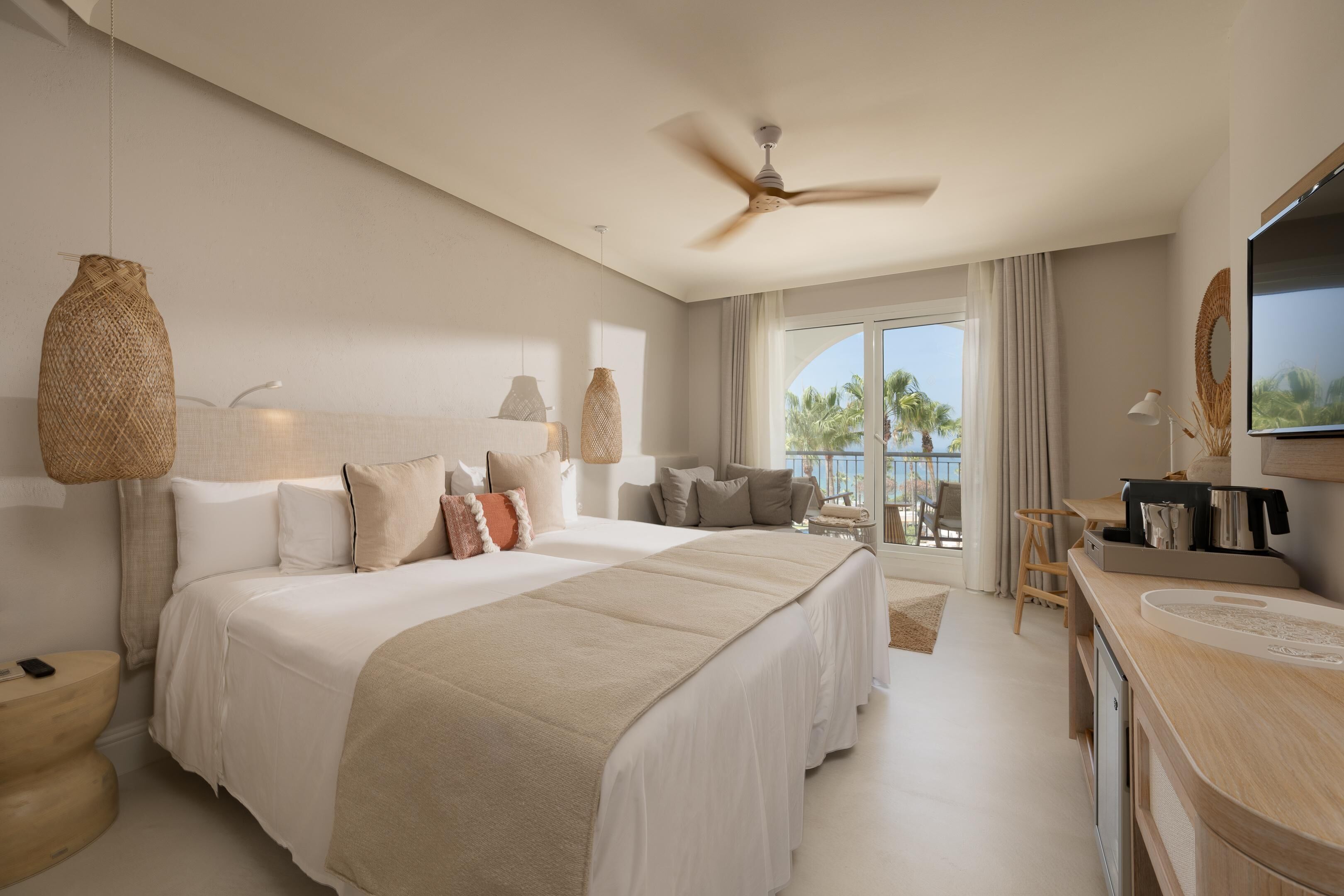 Un dormitorio amplio con una cama grande, un ventilador de techo y vistas al exterior.