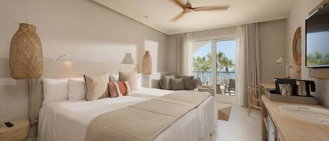 Un dormitorio amplio con una cama grande, un ventilador de techo y vistas al exterior.