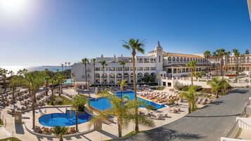 Un resort con una piscina grande, palmeras y vista al océano.