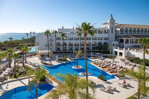 Un complejo turístico con una piscina grande, varios balcones y vistas al mar.