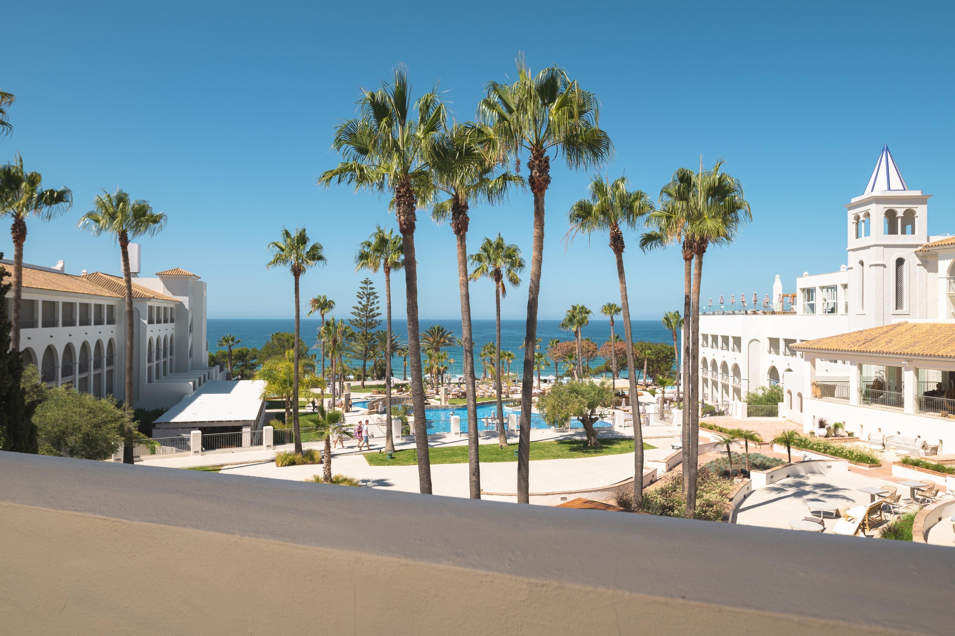 Ein Resort mit Pool, Palmen und Blick auf den Ozean.