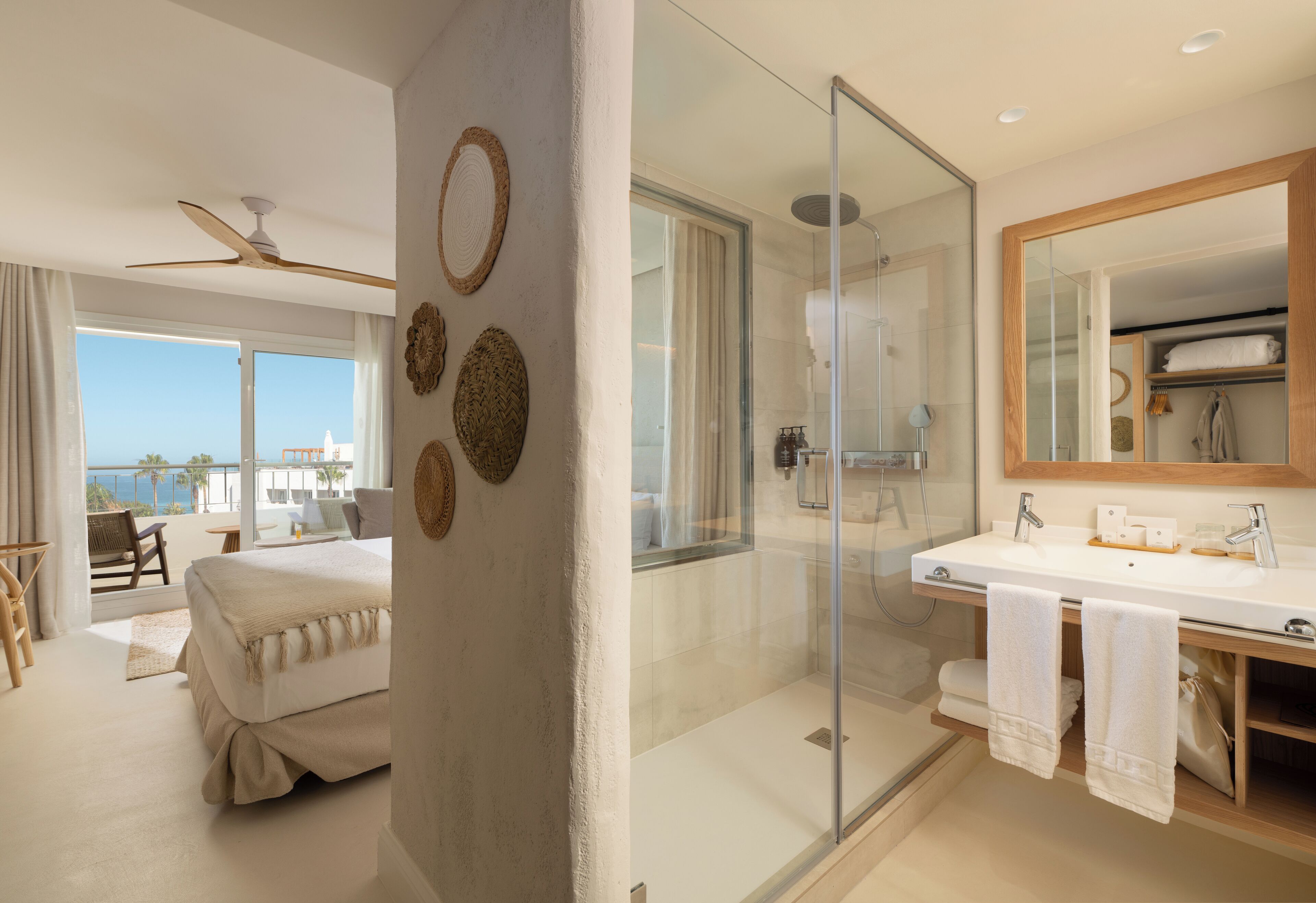 A modern hotel room with a balcony, a glass-enclosed shower, and a large mirror.