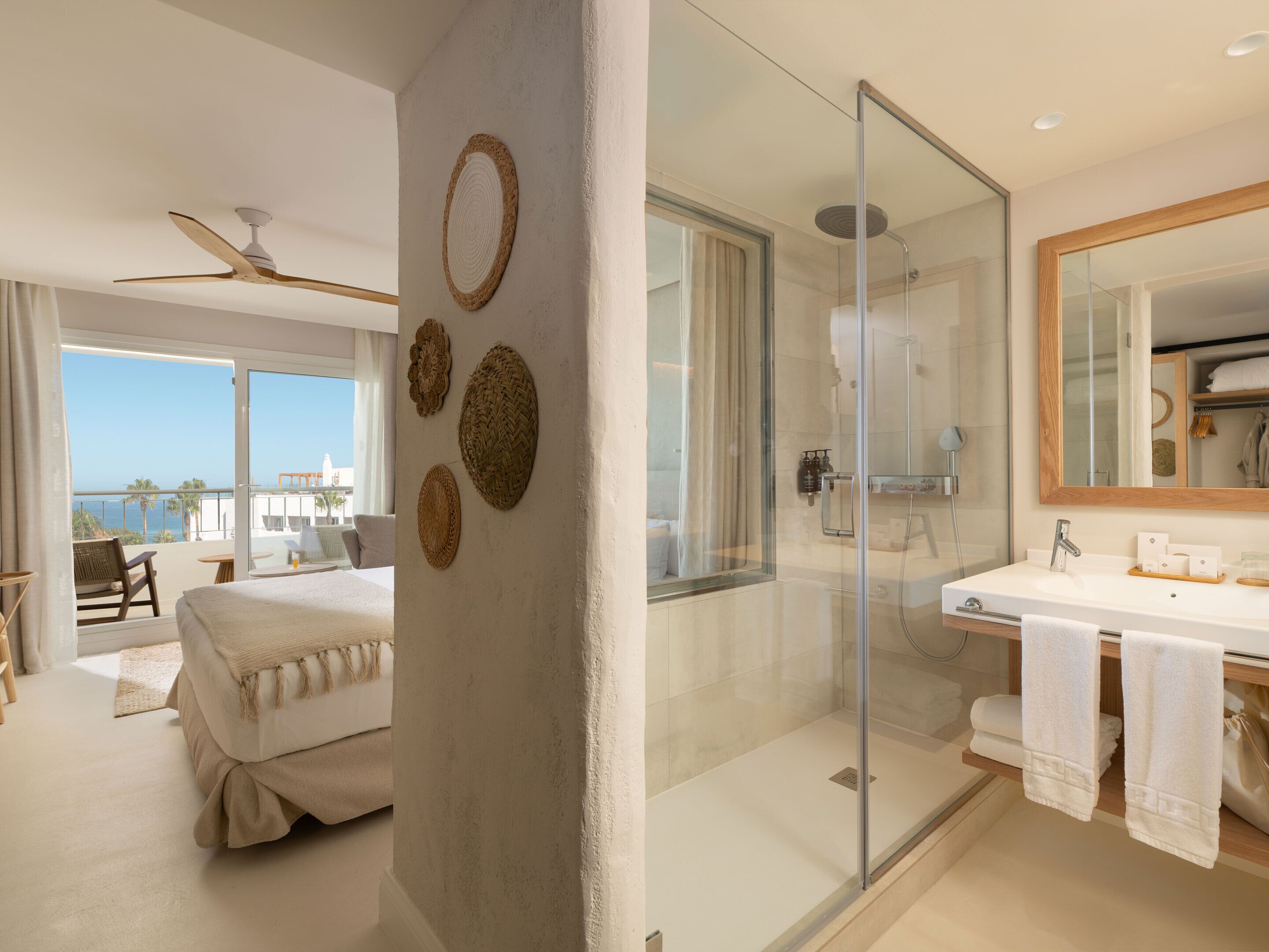 Een moderne hotelkamer met balkon, een douchecabine van glas en een grote spiegel.