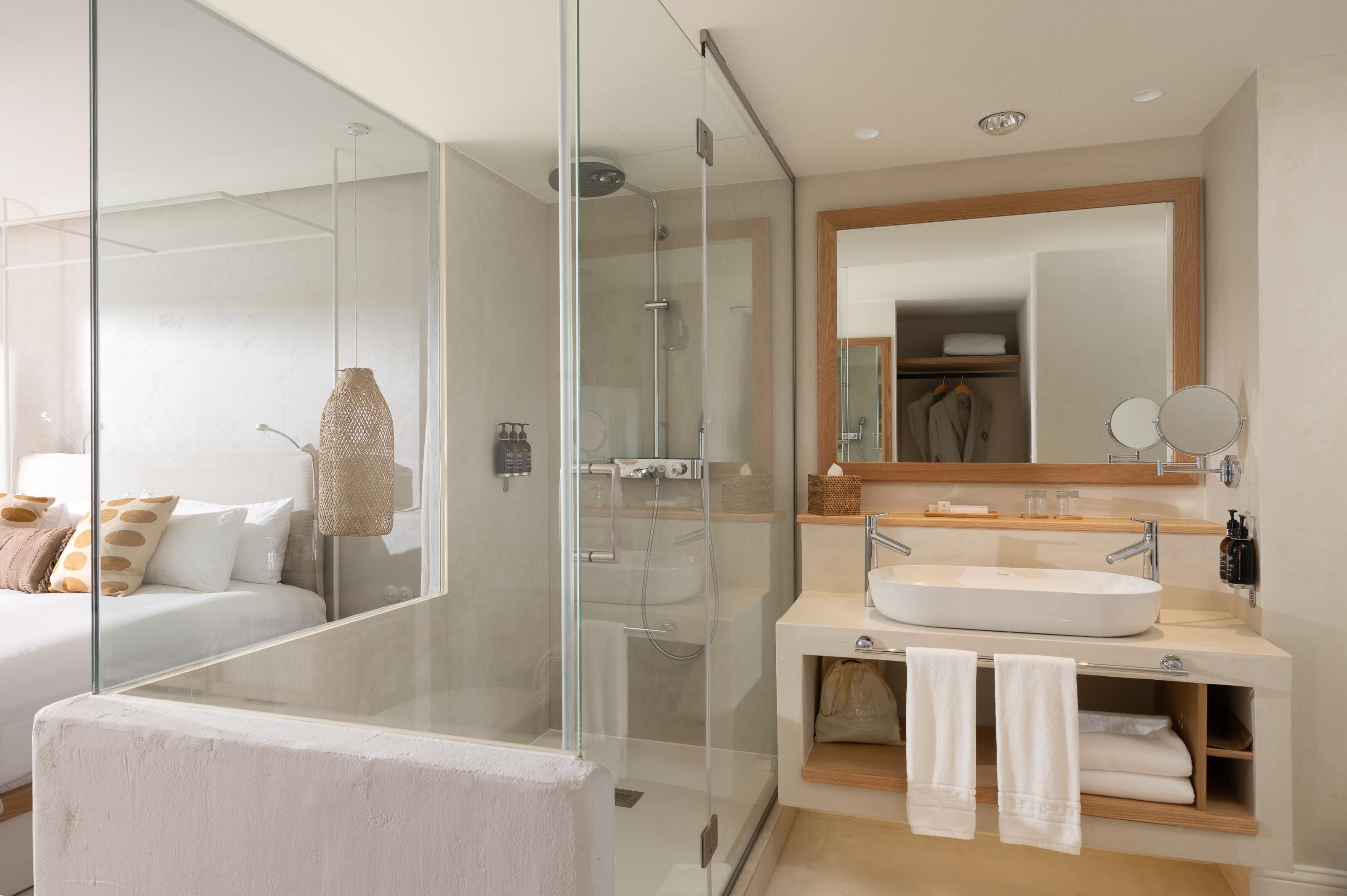 A modern bathroom with a glass-enclosed shower, a large mirror, and a sink with towels.