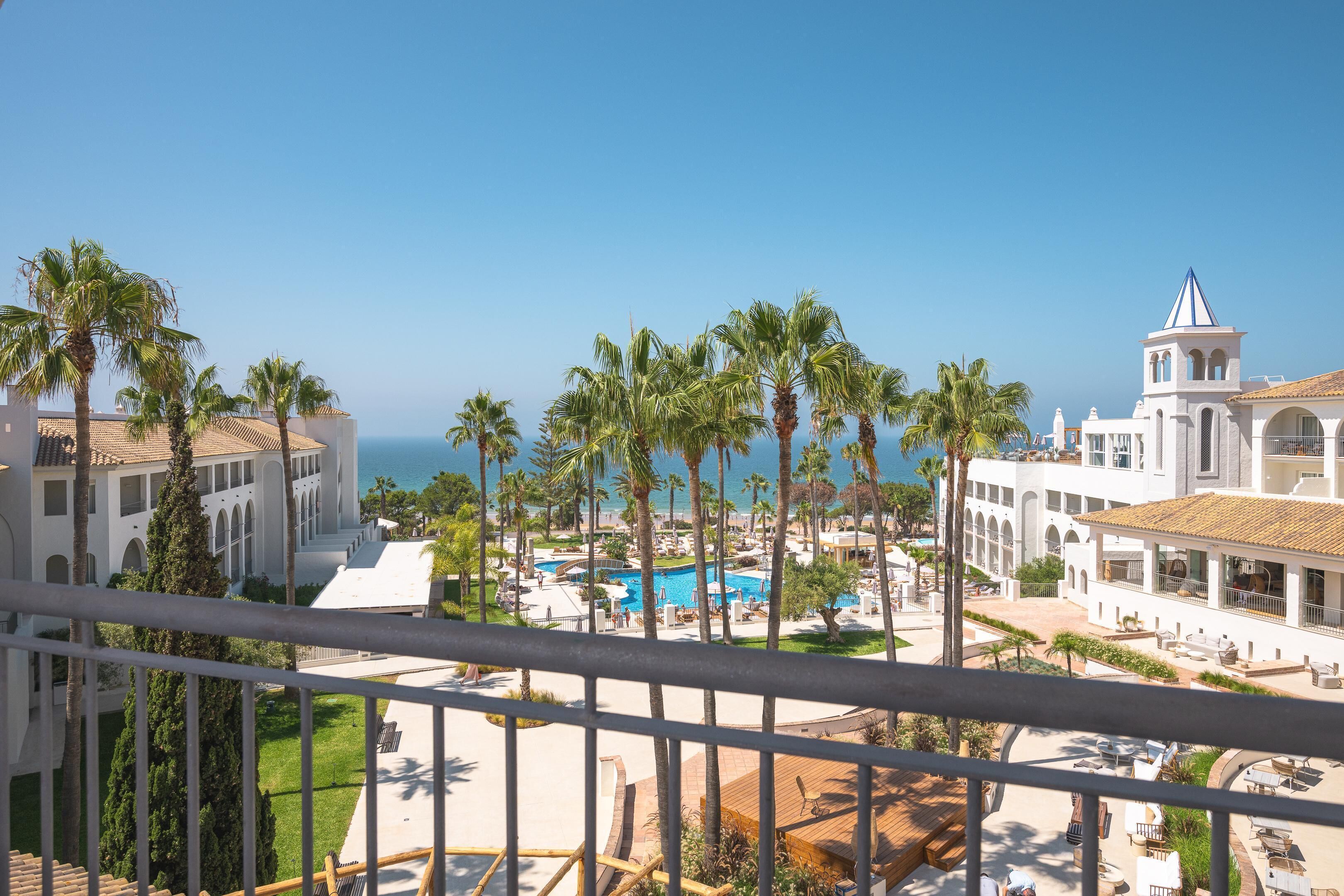 Un resort con piscina, palmeras y vista al océano.