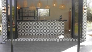 A bar area with a patterned wall, hanging pendant lights, and a counter. - The les deux palmiers Marrakech Complex (Marrakech)