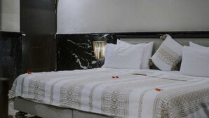 A bed with a patterned bedspread, a headboard with a light fixture, and a marble wall. - The les deux palmiers Marrakech Complex (Marrakech)