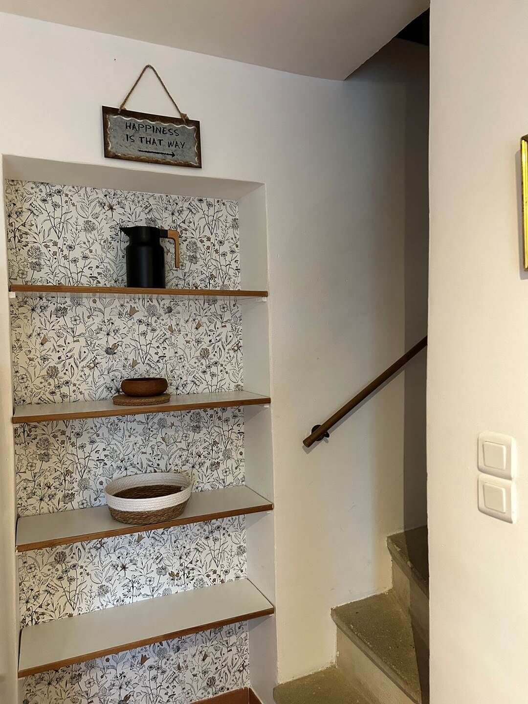 Un escalier avec une rampe en bois et une pancarte au-dessus indiquant : « LE BONHEUR SE TROUVE DE CE CÔTÉ ».