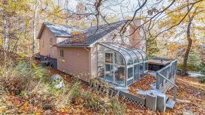 A small, rustic cabin with a glass extension, surrounded by autumn foliage. - Belle of the Chesapeake Bay (Lusby)