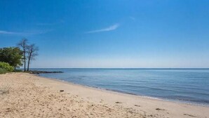 A beach with clear skies, calm water, and a few trees. - Belle of the Chesapeake Bay (Lusby)