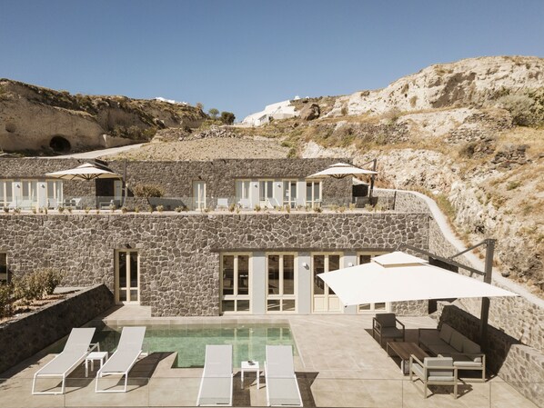 A stone building with a pool, lounge chairs, and outdoor seating.