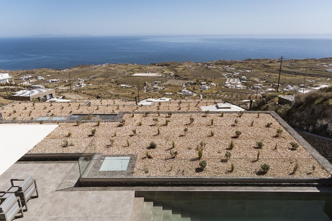 Une terrasse sur le toit offrant une vue sur la mer et un petit village en contrebas.