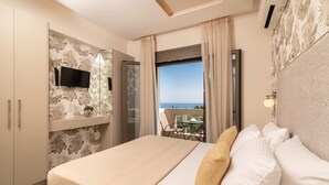 A bedroom with a large bed, a TV mounted on the wall, and a balcony with a view. - Lazai Villa (Zakynthos)
