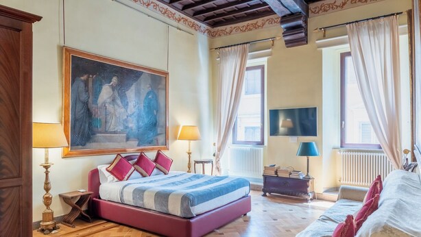 A bedroom with a large bed, a television, and a painting on the wall. - Suites Rome (Rome)