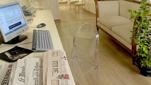A modern office with a curved staircase, a desk with a computer, keyboard, and newspapers, and a sofa in the background. - Suites Rome (Rome)