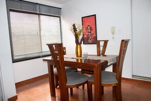 Enjoy meals in this cozy dining area with a wooden table, four chairs, and a vase with dried flowers.