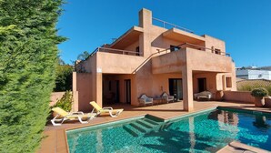 Une maison à deux étages avec une piscine et un espace extérieur aménagé pour se détendre.