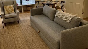 Una sala de estar con sofá, sillón y mesa de comedor.