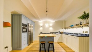 Una cocina moderna con una isla central, taburetes de bar, horno empotrado y refrigerador de acero inoxidable.