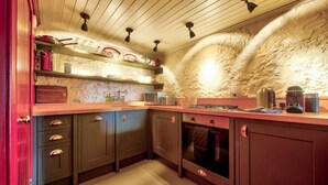Een keuken met houten kastjes, een marmeren aanrechtblad en een stenen muur.