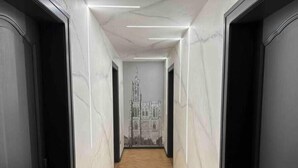 Un pasillo con paredes de mármol y suelo de madera que conduce a una habitación con un gran mural de una catedral.