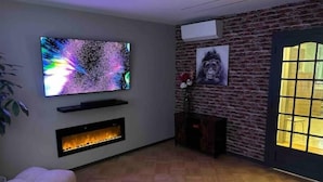 Una sala moderna con televisor de pantalla plana, chimenea y pared de ladrillo.