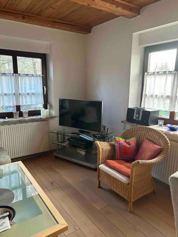 A living room with a television, wicker chair, and a glass coffee table.