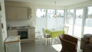 A bright kitchen with a dining area, large windows, and a view of the outside.
