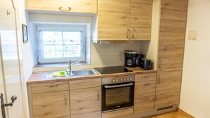 Una cucina moderna con mobili in legno, forno a incasso, lavello e finestra con vista esterna.