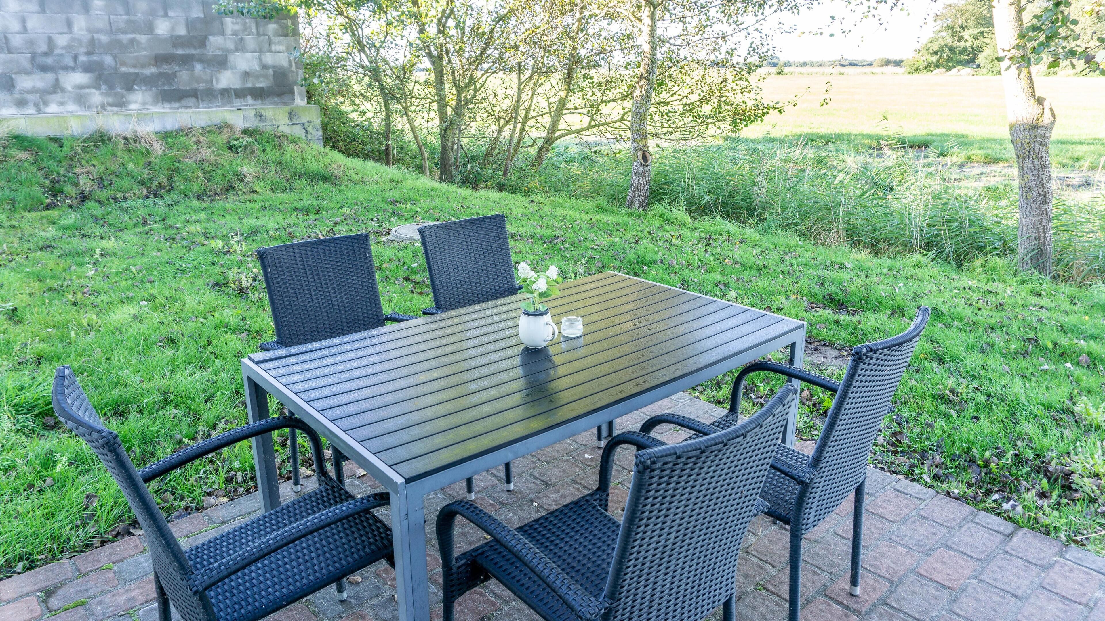 An outdoor patio with a rectangular table and four chairs.