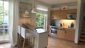 Eine Küche mit einer zentralen Kochinsel, Holzschränken, einer Mikrowelle und einer Kaffeemaschine.