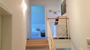 Eine Treppe mit Holzstufen und einem weißen Geländer führt zu einem Schlafzimmer mit einem Bett und einem Nachttisch.