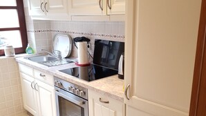 A kitchen with white cabinets, a stainless steel oven, a sink, and a window.