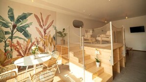 Une pièce avec un lit superposé, une table ronde avec des chaises et une grande fresque murale représentant des plantes.
