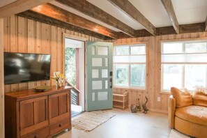 A wooden interior with a television on a cabinet, a door, and a window.