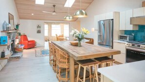A modern kitchen with wooden cabinets, a central island, and stainless steel appliances. - Jus' BeChi A (Folly Beach)