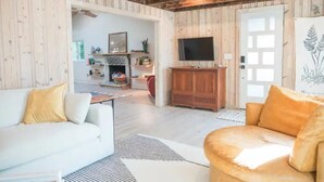A cozy living room with a white sofa, a tan armchair, and a fireplace. - Jus' BeChi A (Folly Beach)