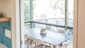 A modern dining area with a wooden ceiling, a glass door leading to an outdoor deck, and a table with chairs. - Jus' BeChi A (Folly Beach)