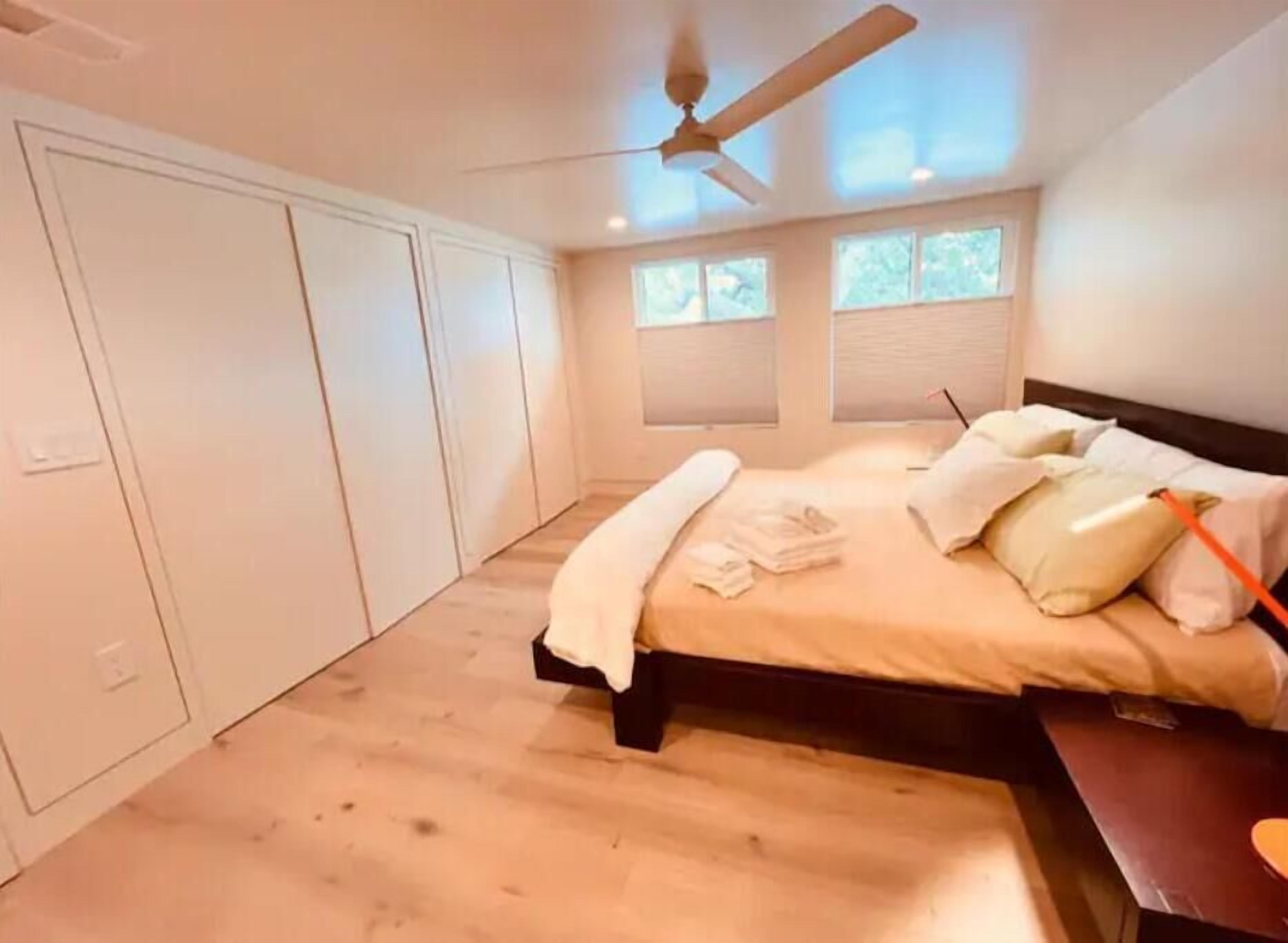 Un dormitorio con una cama, ventilador de techo y ventana.