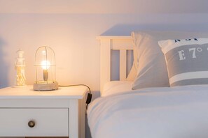 Cozy retreat with a bed and nightstand, featuring a lamp and decorative lighthouse.
