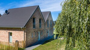 A row of brick buildings with pitched roofs and a well-maintained lawn. - Ferienhaushälfte "zweite Heimat" in Tating für 6 Personen (Tating)