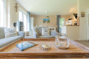 A cozy living room with a sofa, a coffee table with a book and a decorative crab, and a view of the dining area.