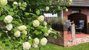 A garden with white hydrangea bushes and a brick planter with plants. - Appartement Eidernest in Garding für 2 Personen (Garding)