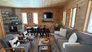 Ein Holzblockhaus-Innenraum mit Essbereich, einer Couch und einer Küche.