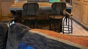 A modern kitchen with wooden cabinets, a central island with bar stools, and pendant lighting. - New! Secluded Cabin w/ Hot Tub, close to Solitude & Brighton Ski Resorts (Brighton)