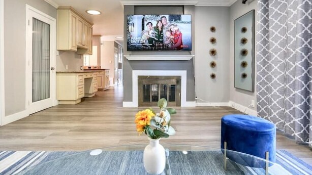 A modern living room with a fireplace, a television mounted above it, and a blue ottoman. - South SJ 4BR: Spacious & Comfy (San Jose)
