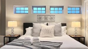 A bedroom with a large bed, two bedside tables with lamps, and three windows. - South SJ 4BR: Spacious & Comfy (San Jose)