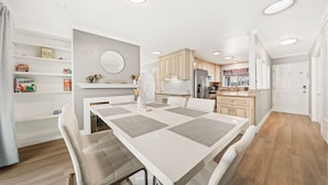 A modern kitchen with white cabinets, a central island, and a dining area with a white table and chairs. - South SJ 4BR: Spacious & Comfy (San Jose)